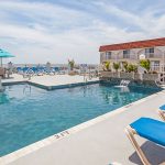 Outdoor pool with lounge chairs and ocean view at Days Inn and Suites Wildwood
