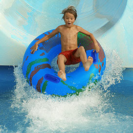 boy on an inflatable tube sliding down a water park slide